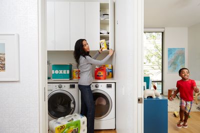 A woman holds Clorox while doing the laundry